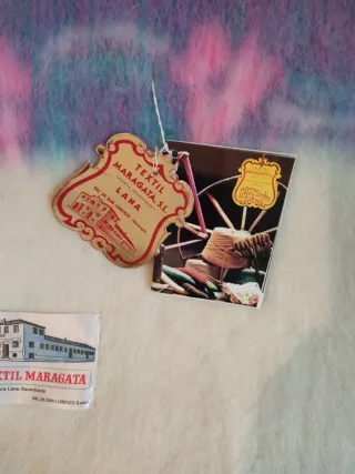 Manta de lana beige con flores moradas.