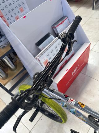 Bicicleta BMX plateada con ruedas verdes