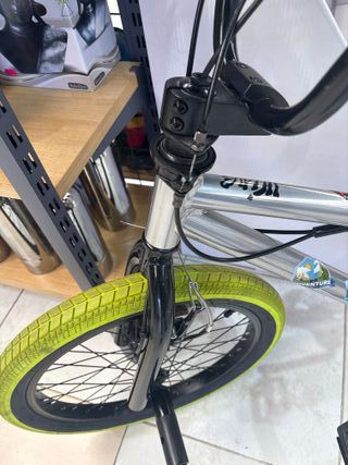 Bicicleta BMX plateada con ruedas verdes