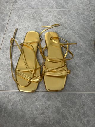Sandalias doradas atadas a la pierna