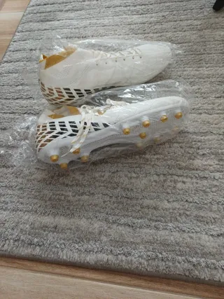 Botas de fútbol blancas y doradas