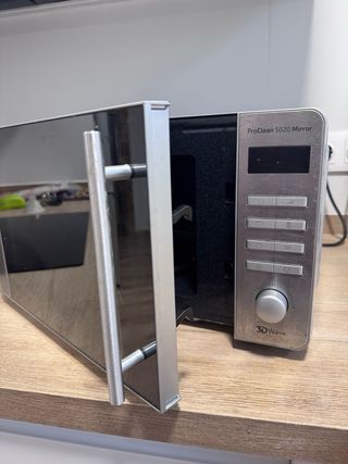 Microondas plateado con puerta de cristal