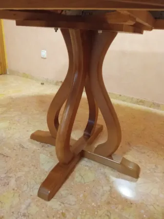 Mesa de comedor redonda de madera y cuatro sillas.