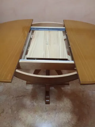 Mesa de comedor redonda de madera y cuatro sillas.
