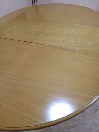 Mesa de comedor redonda de madera y cuatro sillas.
