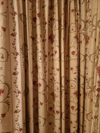 Cortinas de tela beige con flores rojas.