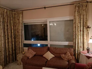 Cortinas de tela beige con flores rojas.