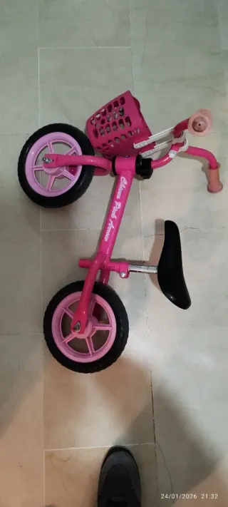 Bicicleta rosa sin pedales con cesta