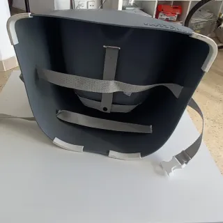 Silla de bebé gris con arnés.