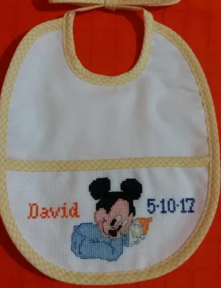 Babero bordado a mano punto de cruz, color rosa.