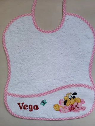 Babero bordado a mano punto de cruz, color rosa.