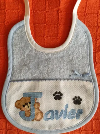 Babero bordado a mano punto de cruz, color rosa.