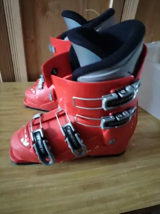 Botas de esquí rojas, tablas y bastones