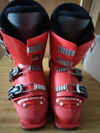 Botas de esquí rojas, tablas y bastones