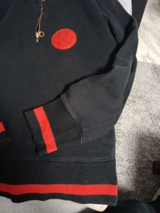 Sudadera negra con cremallera y detalles rojos