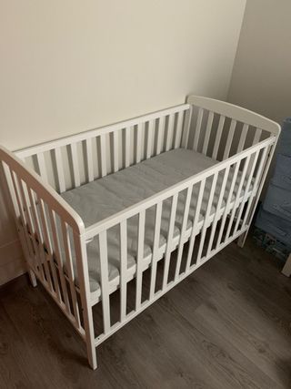 Cuna de bebé blanca de madera con colchon.