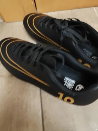Botas de fútbol negras y doradas nuevas a estrenar