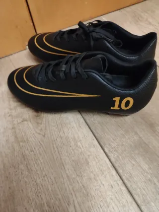 Botas de fútbol negras y doradas nuevas a estrenar