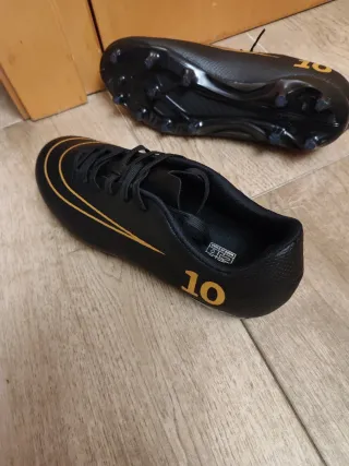 Botas de fútbol negras y doradas nuevas a estrenar