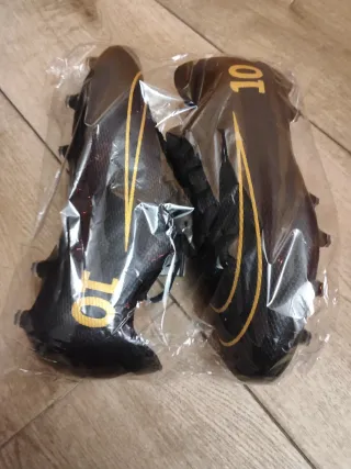 Botas de fútbol negras y doradas nuevas a estrenar