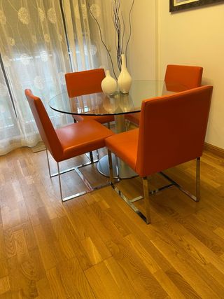 Mesa cristal y 4 sillas de piel en color naranja.