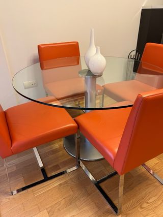 Mesa cristal y 4 sillas de piel en color naranja.