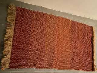 Alfombra tejida naranja y roja con flecos