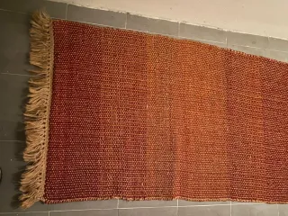 Alfombra tejida naranja y roja con flecos