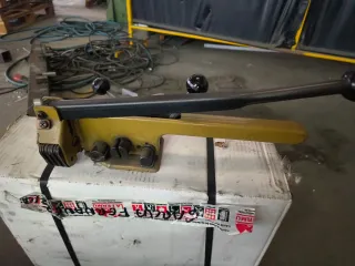 Máquina flejadora con rollo de fleje y grapas.