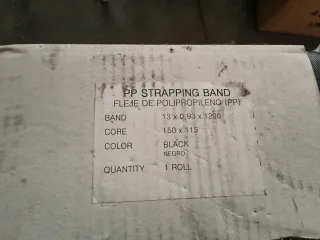 Máquina flejadora con rollo de fleje y grapas.