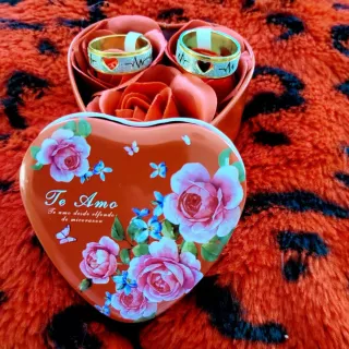 Anillos de oro en caja de corazón con rosas
