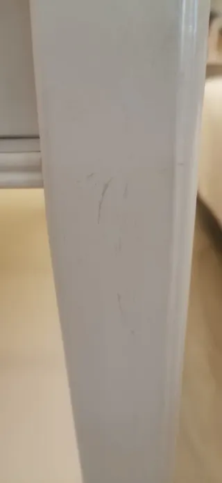 Mesa de centro blanca con tapa de cristal y cajón.