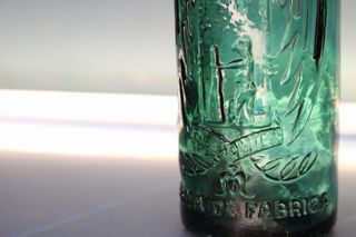 Botella antigua El Águila, verde, con relieve.