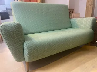 Sofá verde de tela con patas de madera