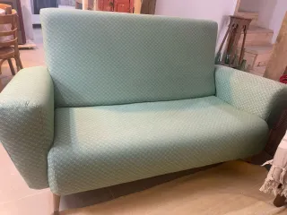 Sofá verde de tela con patas de madera