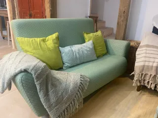Sofá verde de tela con patas de madera
