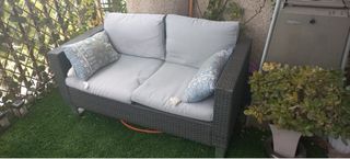 Sofá de terraza gris con cojines dorados