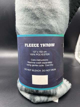 Manta polar gris y negra con etiqueta