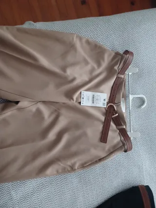 Pantalónes rectos, beige y negro con cinturón.