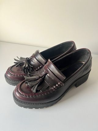 Mocasines de mujer con borlas en tono burdeos.