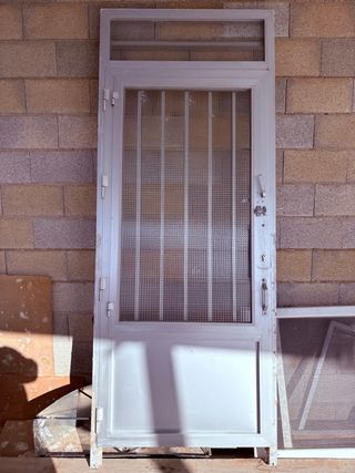 Puerta aluminio gris con reja y cristal