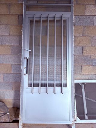 Puerta aluminio gris con reja y cristal