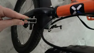 Bicicleta infantil naranja con cesta y ruedines.