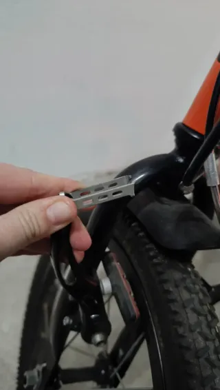 Bicicleta infantil naranja con cesta y ruedines.