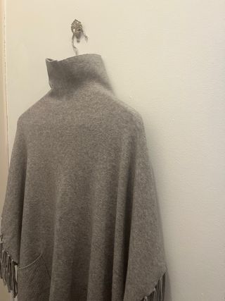 Poncho gris con cuello alto y flecos