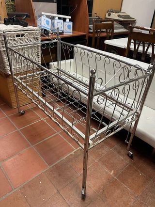 Cuna de metal antigua con ruedas