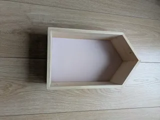 Estante de madera con fondo rosa y forma de casita