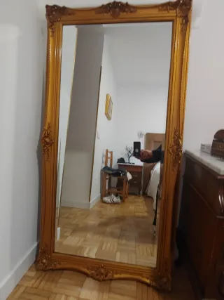 Espejo de pared clasico con ornamentos tallados.