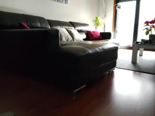 Sofá de piel negro , con patas de acero.