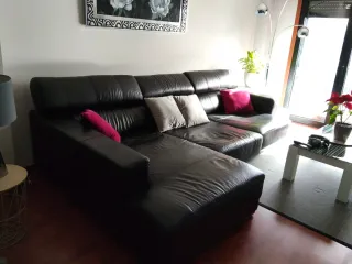 Sofá de piel negro , con patas de acero.